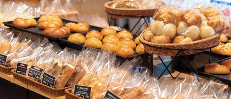 A bakery display with various breads and pastries in baskets and plastic packaging.