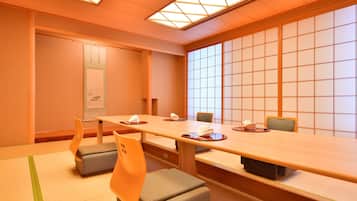 Un salón de conferencias con una larga mesa, sillas, esteras de tatami y paneles shoji.