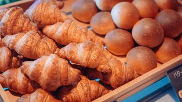 A display of baked goods including croissants and round bread.