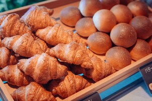 A display of baked goods including croissants and round bread.