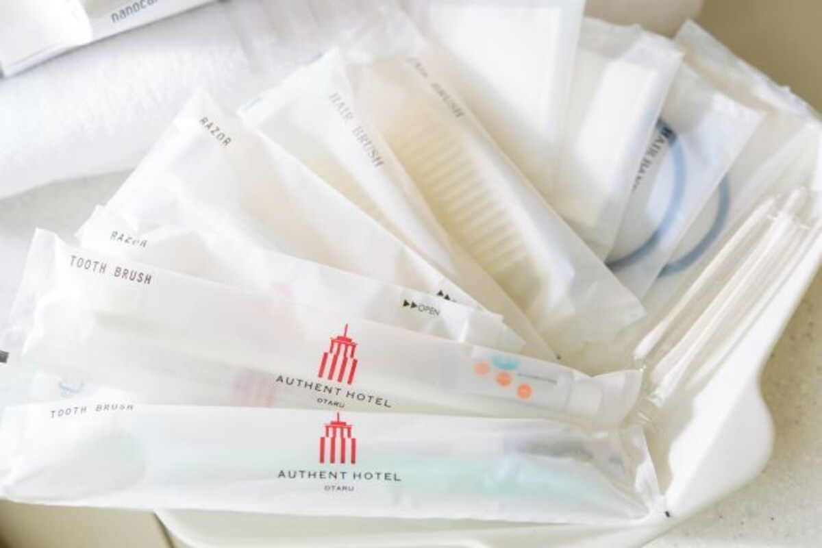 A collection of toiletries in a plastic bag, including toothbrushes and razors, with the 'Authent Hotel' branding visible.