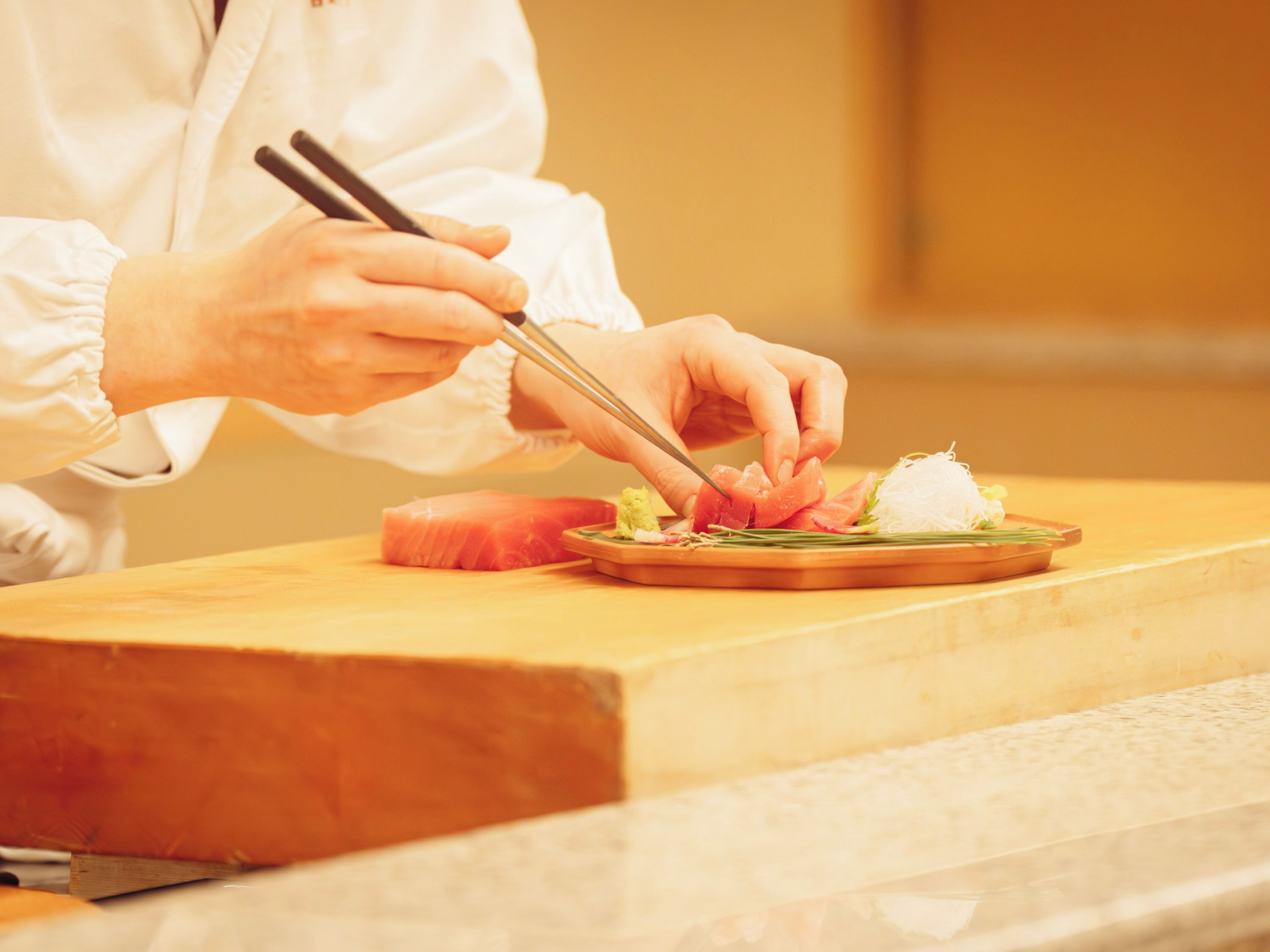 A person preparing food at a counter with a knife and chopsticks.
