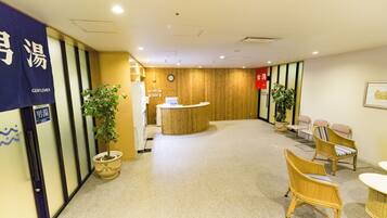 A reception area with a wooden reception desk, potted plants, and wicker chairs.