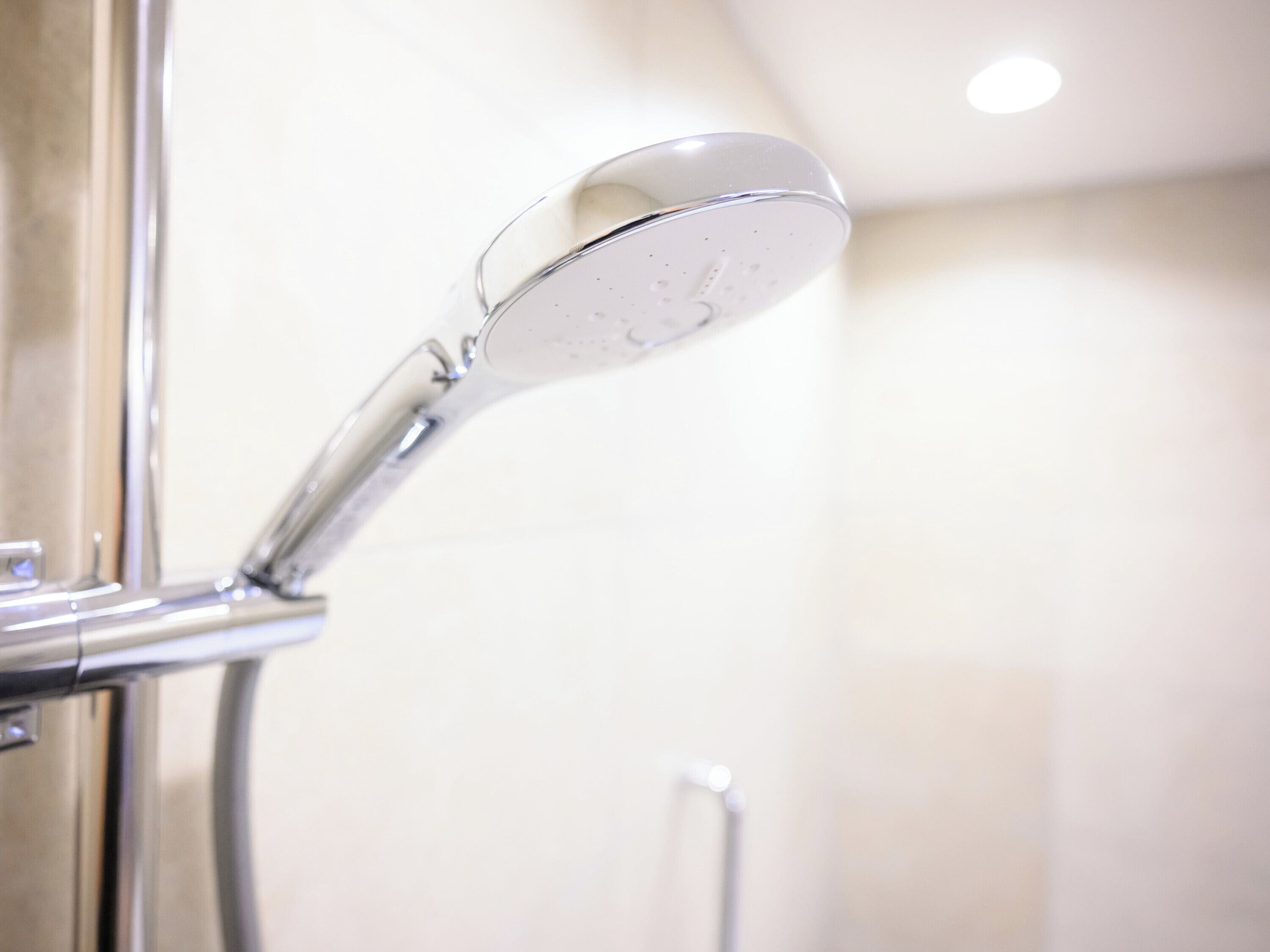 A chrome showerhead with a curved design, mounted on a wall.