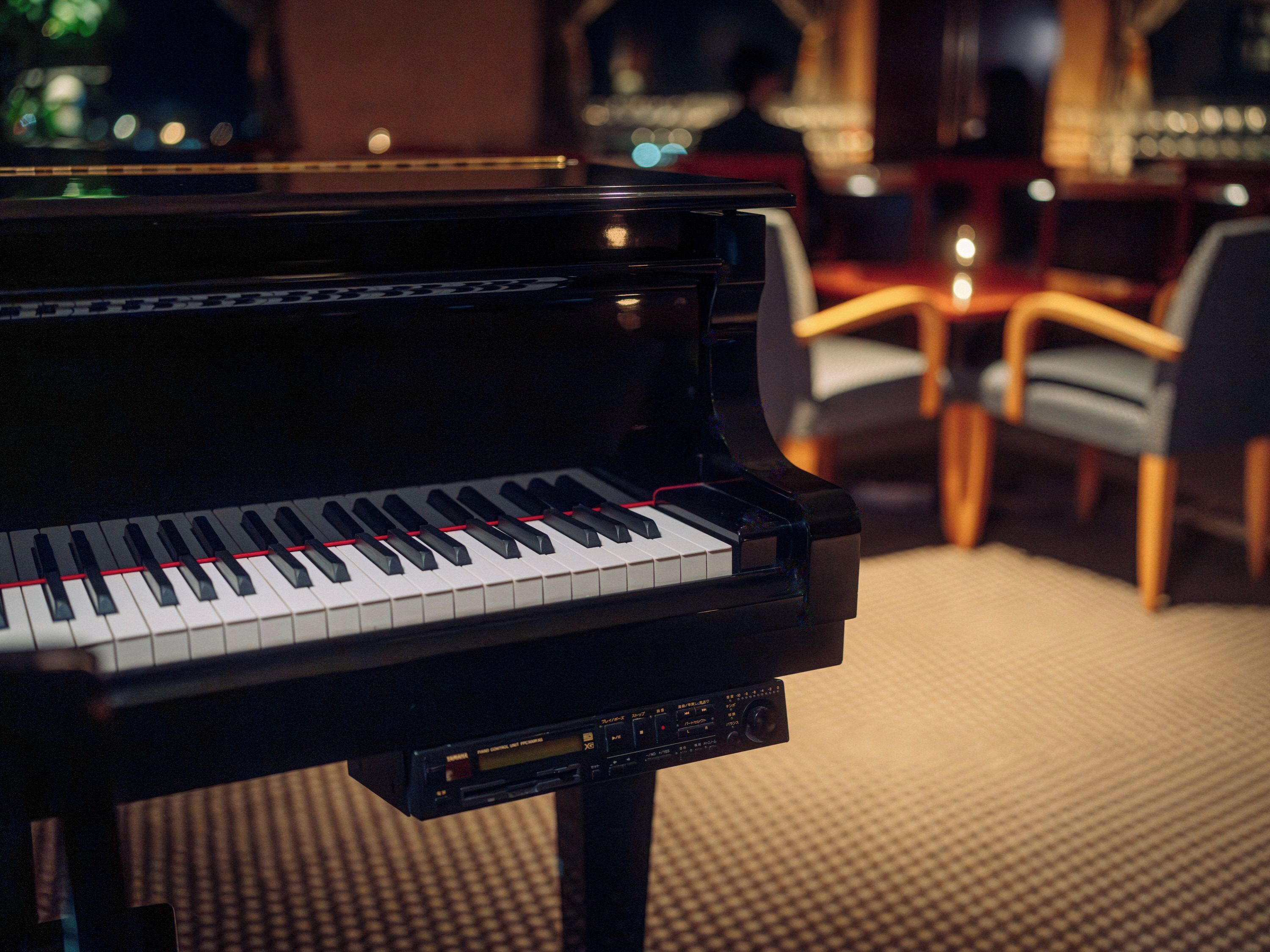 A grand piano in a room with a carpeted floor and chairs.