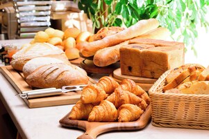 Variedad de productos horneados, incluyendo pan, croissants y pastelería, sobre una mesa de madera.