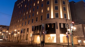 Un hotel de varios pisos con una fachada curva, ventanas iluminadas y una estructura circular destacada en la parte superior.