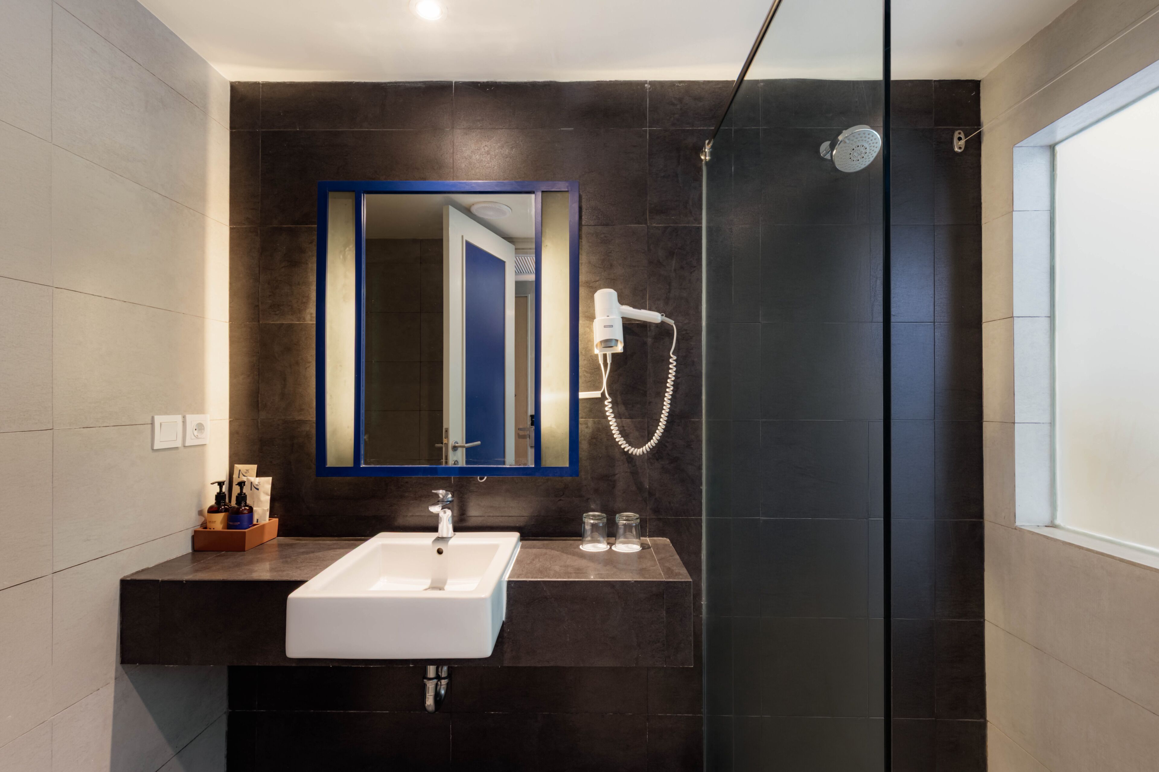 A modern bathroom with a large mirror, a white sink, and a shower area.