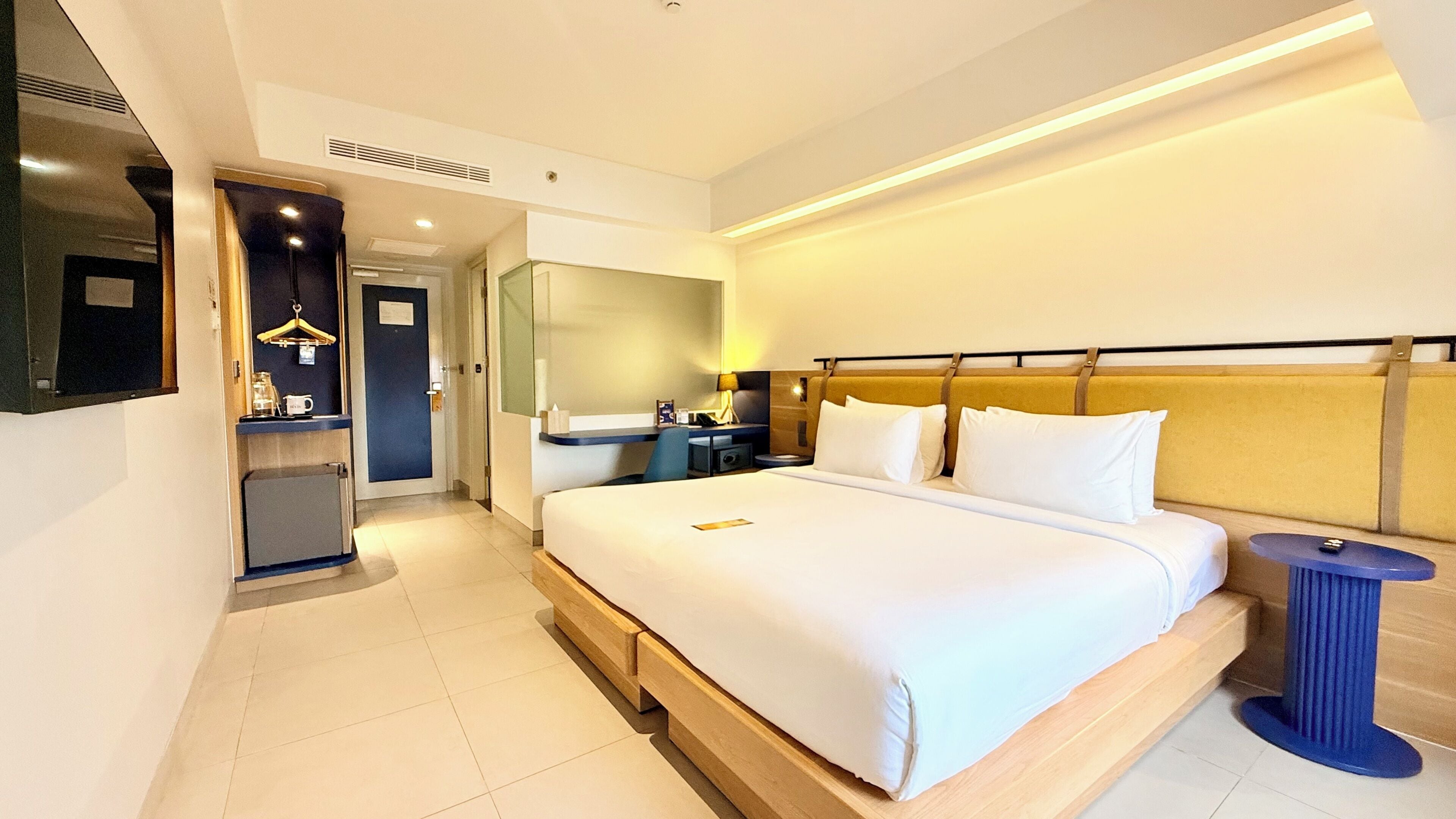 Ein Hotelzimmer mit Bett, Nachttisch, Lampe und Spiegel.