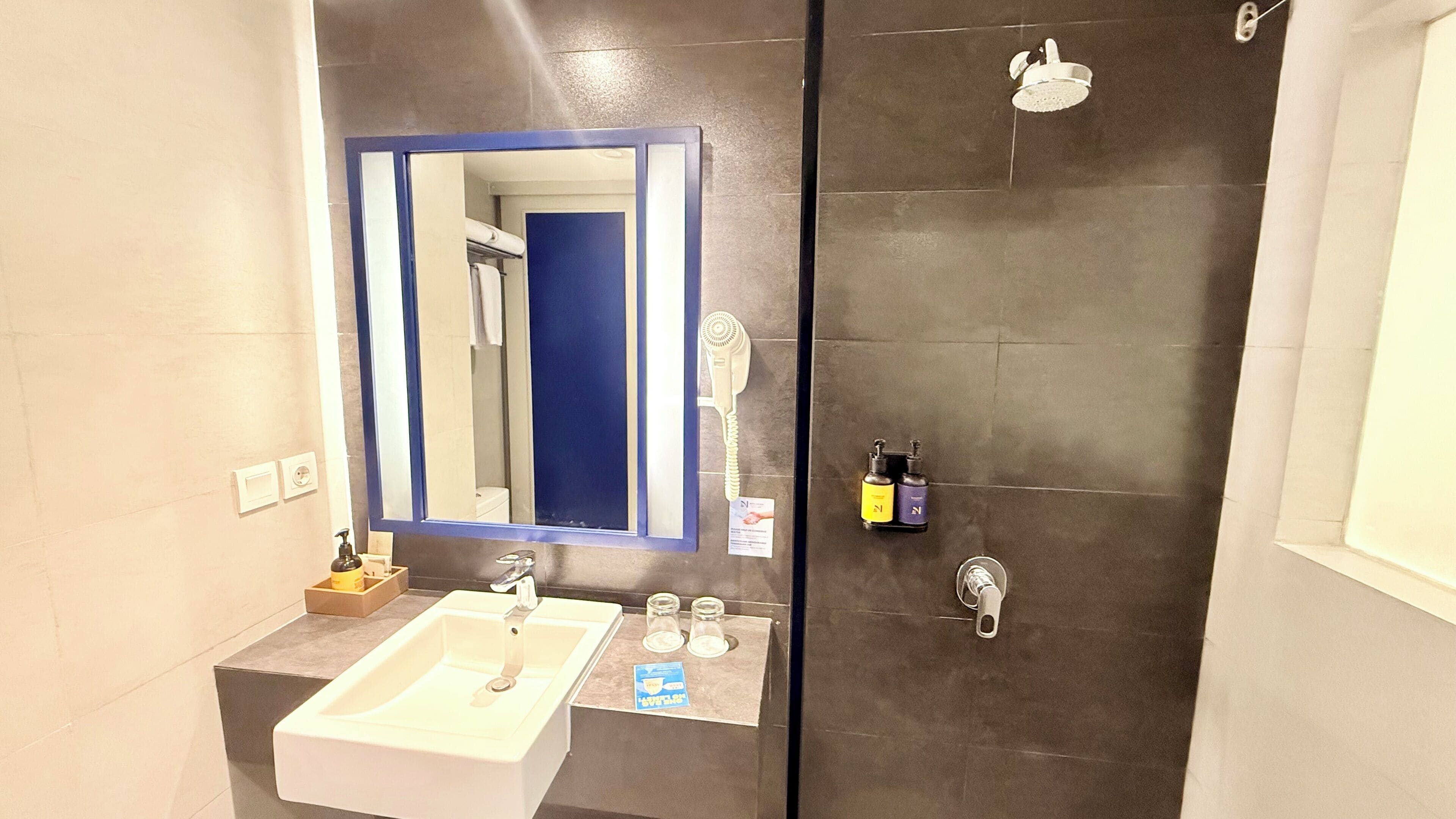 A bathroom with a sink, mirror, and two shower stalls.
