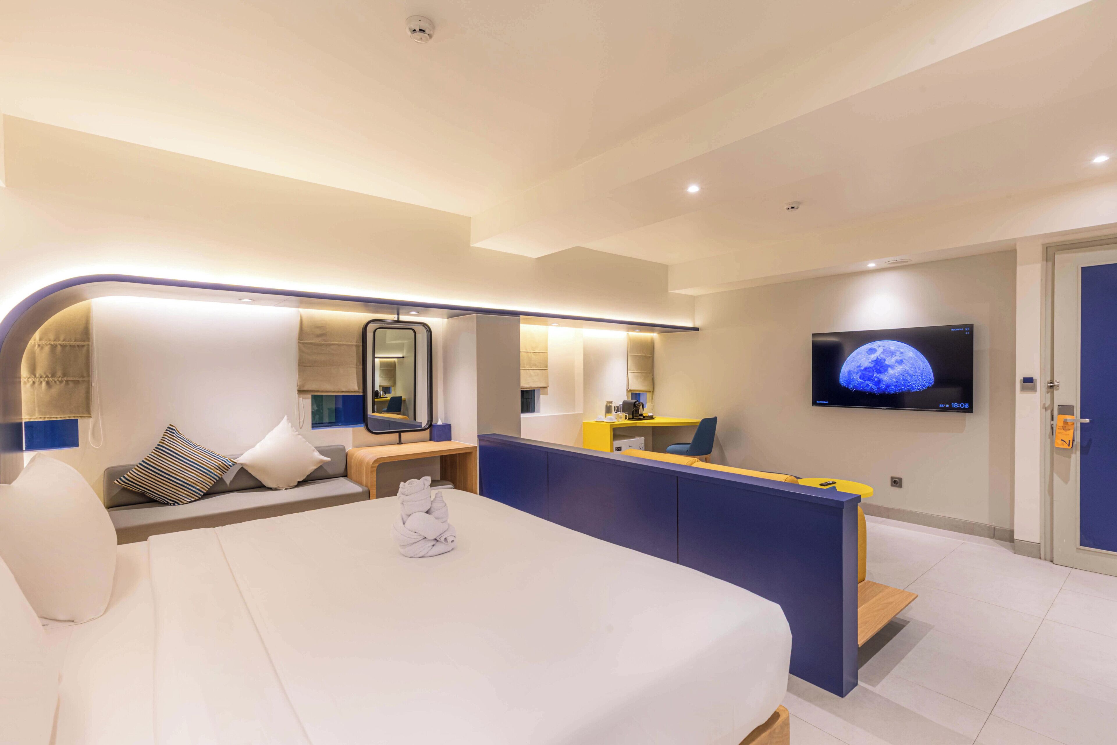 Una habitació d'hotel moderna amb un llit gran, un escriptori, un televisor i un bany.