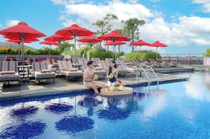 Una piscina al aire libre, sombrillas, sillones reclinables de piscina