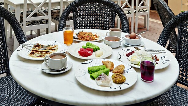 A dining area with multiple tables and chairs, a staircase, and a view of the upper floor. - Palace Hotel (Kuala Lumpur)