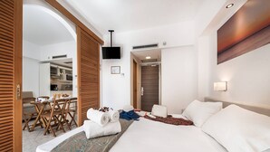 Una camera d'albergo con un letto, una scrivania con sedie, una televisione e angolo cottura.