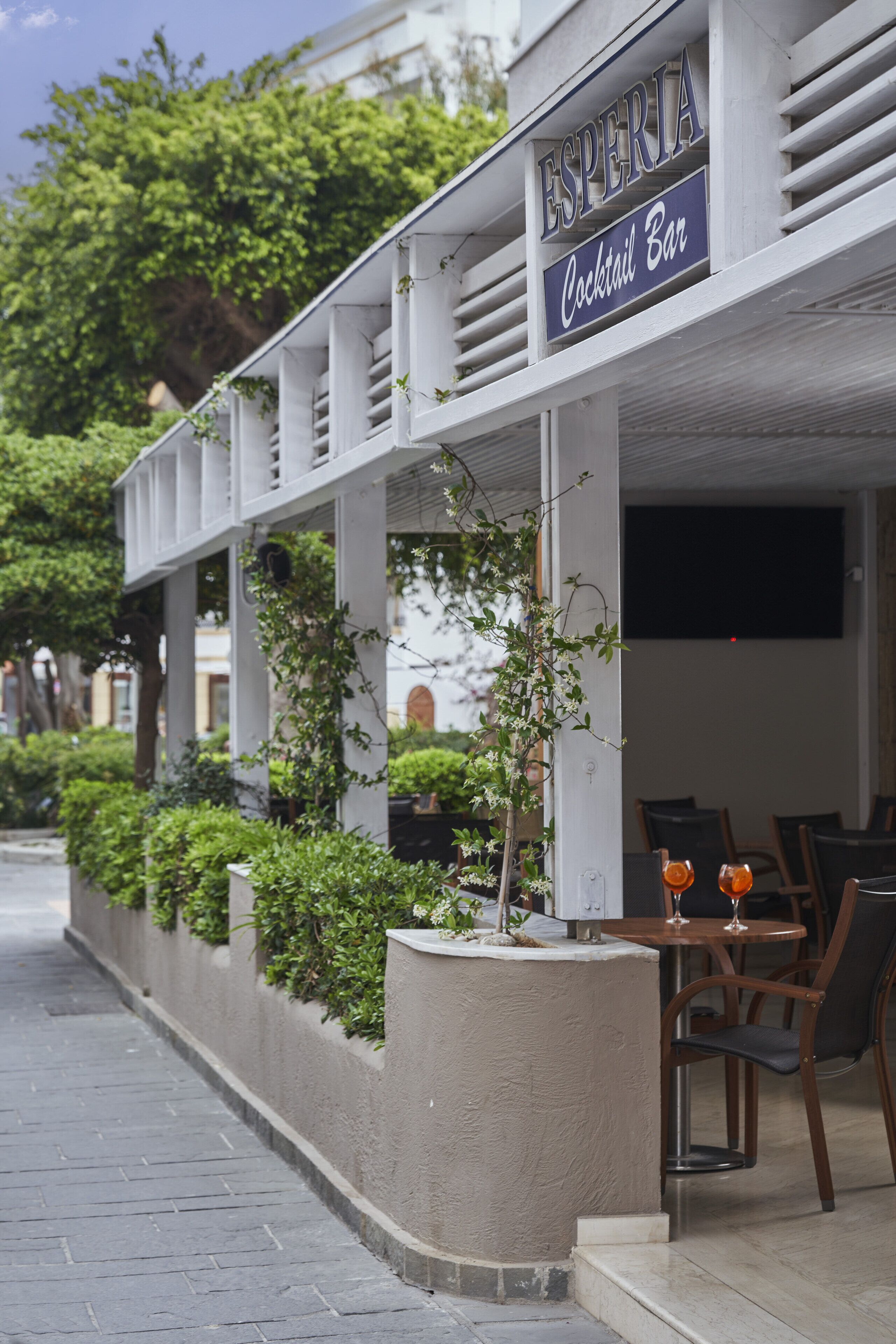 A cocktail bar named "Esperia" with outdoor seating and greenery.