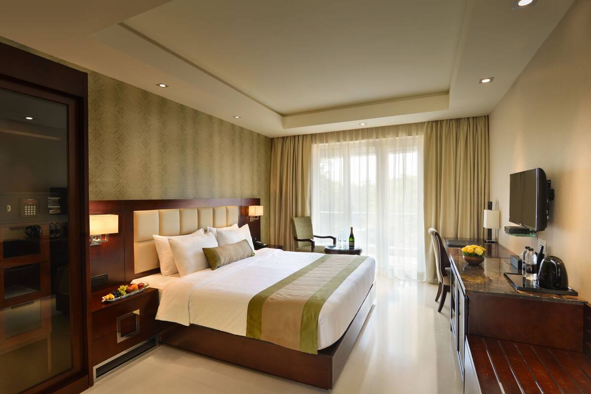 Ein Hotelzimmer mit einem großen Bett, einem Schreibtisch mit Stuhl, einem Fernseher und einer Minibar.