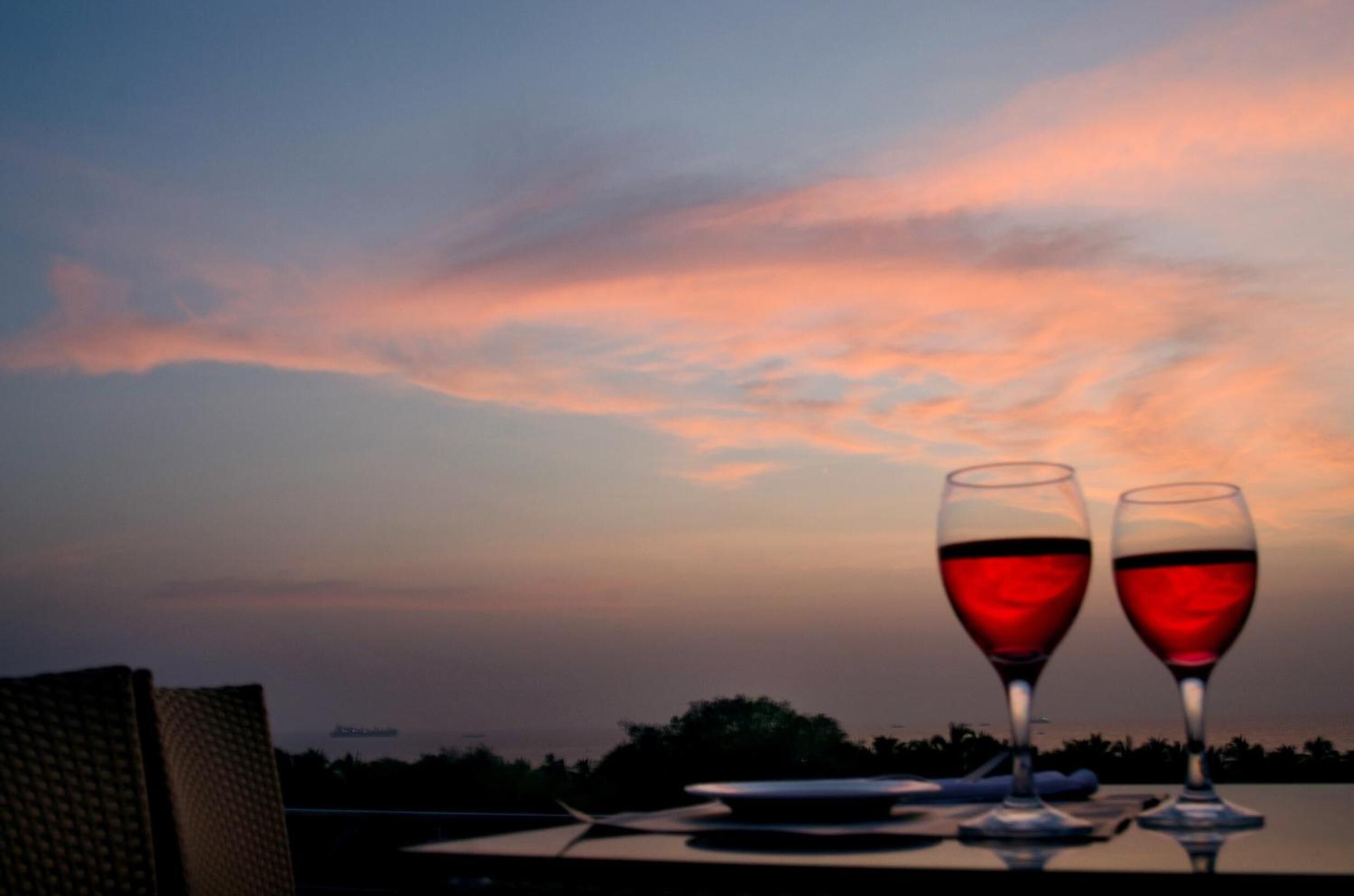 Two wine glasses on a table with a sunset view.