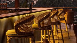 Un rincón de bar con sillas de mimbre y lámparas colgantes.