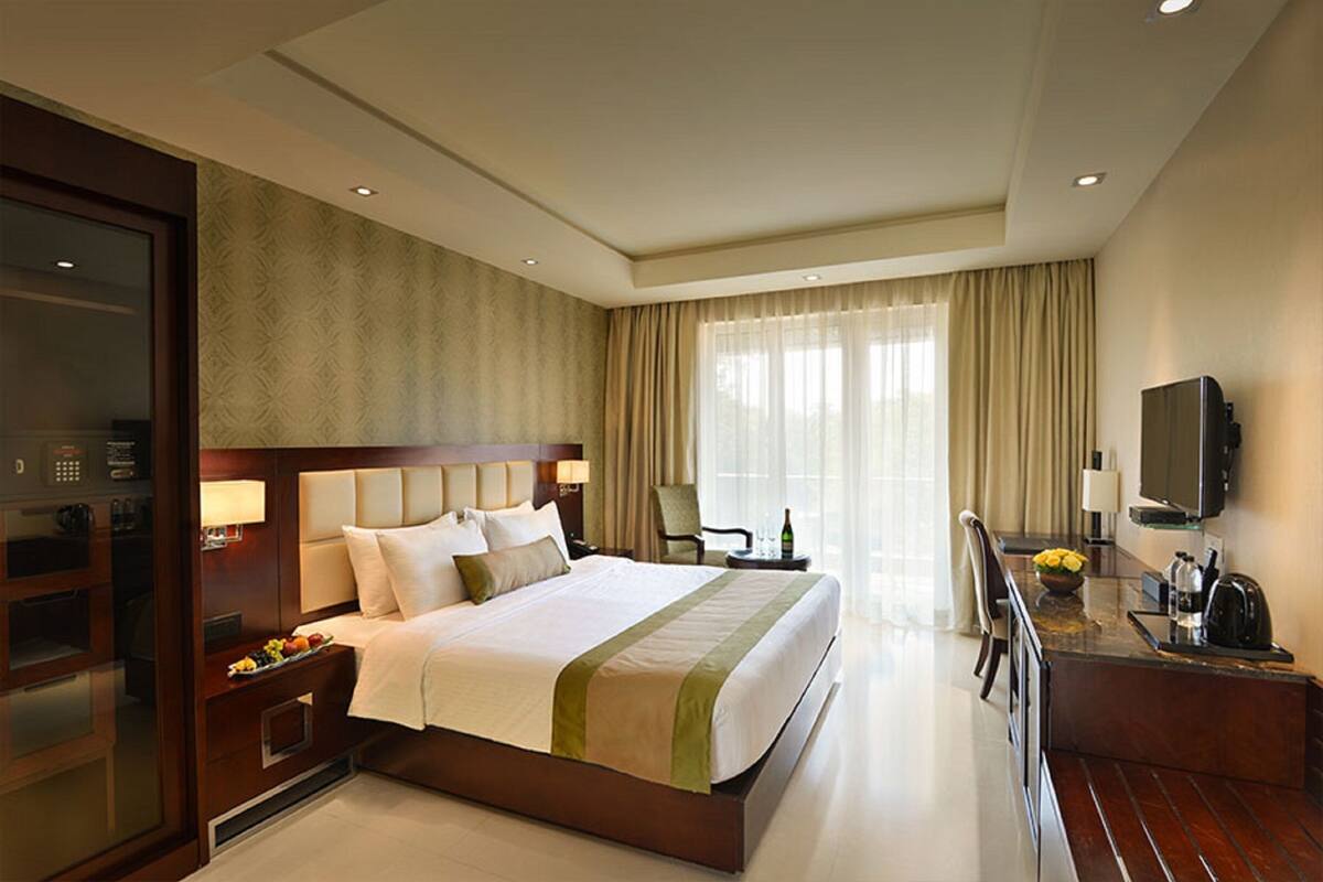 Ein Hotelzimmer mit einem großen Bett, einem Schreibtisch mit Stuhl, einem Fernseher und einer Minibar.