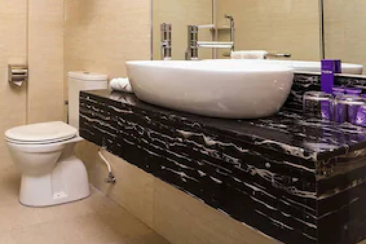 A modern bathroom with a large mirror, a white sink, and a toilet.