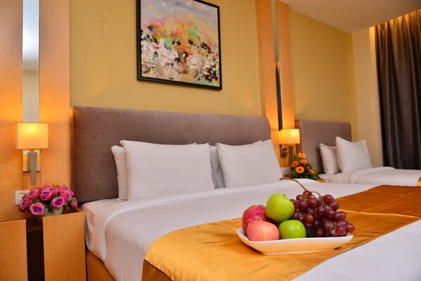 Una habitación de hotel con dos camas, un frutero sobre la cama y un cuadro en la pared.