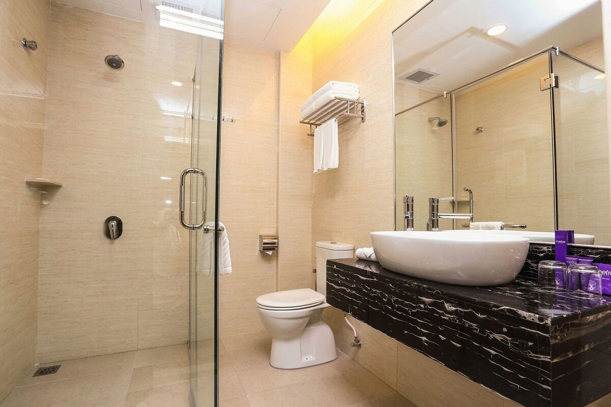 Un baño moderno con ducha de vidrio, inodoro blanco y lavamanos grande con encimera de mármol.