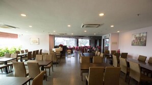 A spacious dining area with multiple tables and chairs, a reception desk, and large windows providing natural light. - Metro Hotel (Kuala Lumpur)