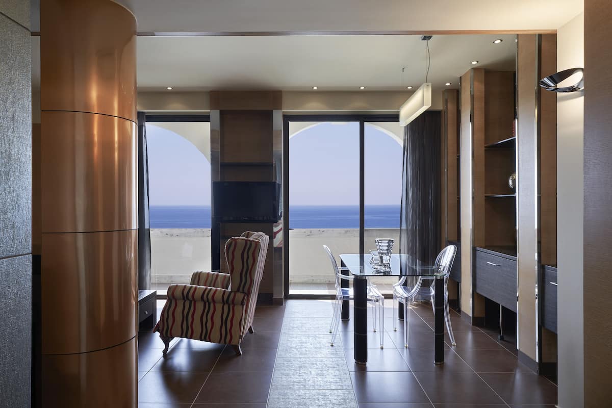 Una habitación moderna con balcón, una mesa de comedor con sillas y un televisor.