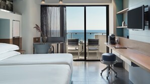 Una habitación de hotel moderna con balcón, cama, escritorio y televisor.