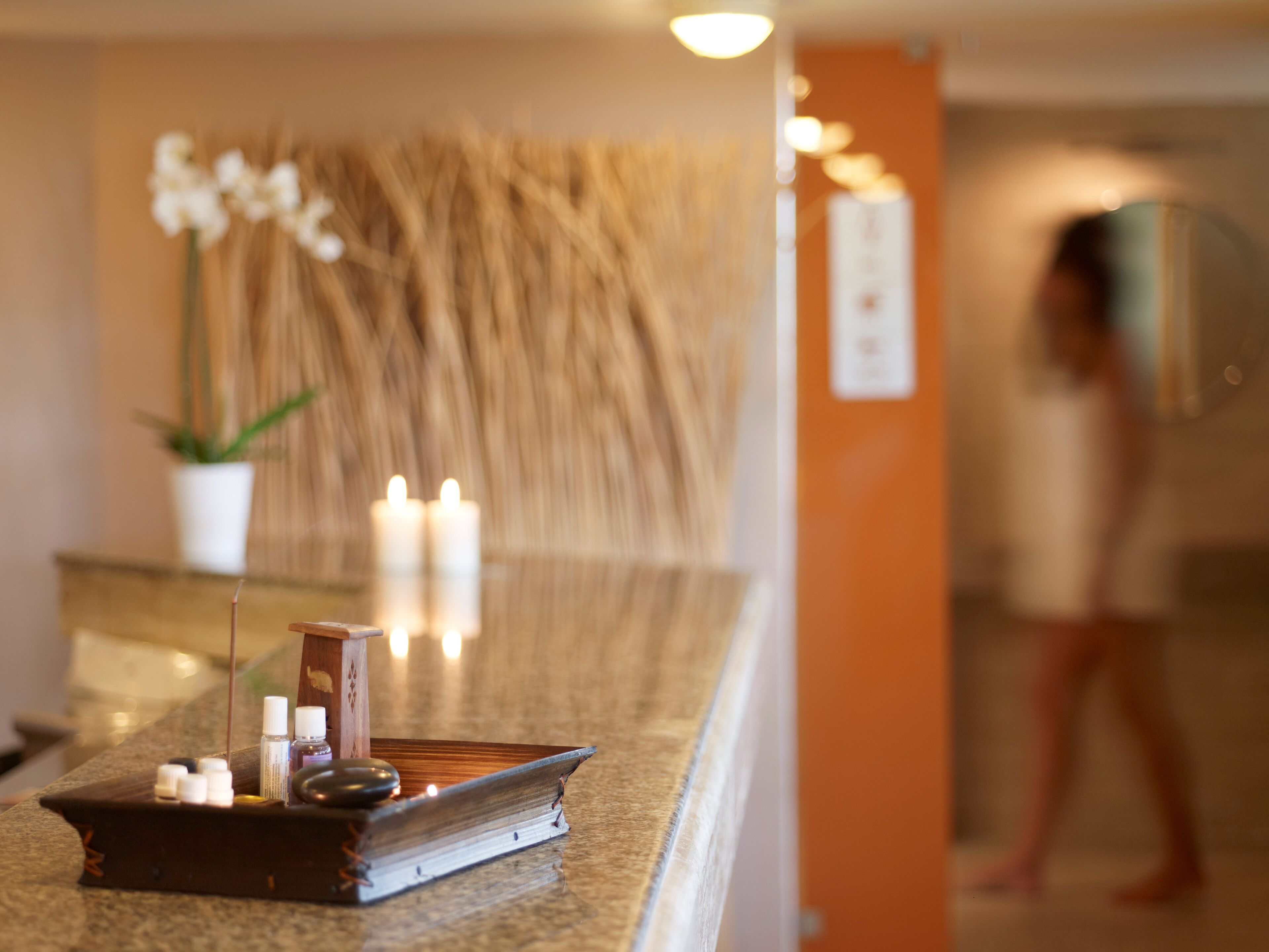 A reception desk with candles, a small plant, and a book.