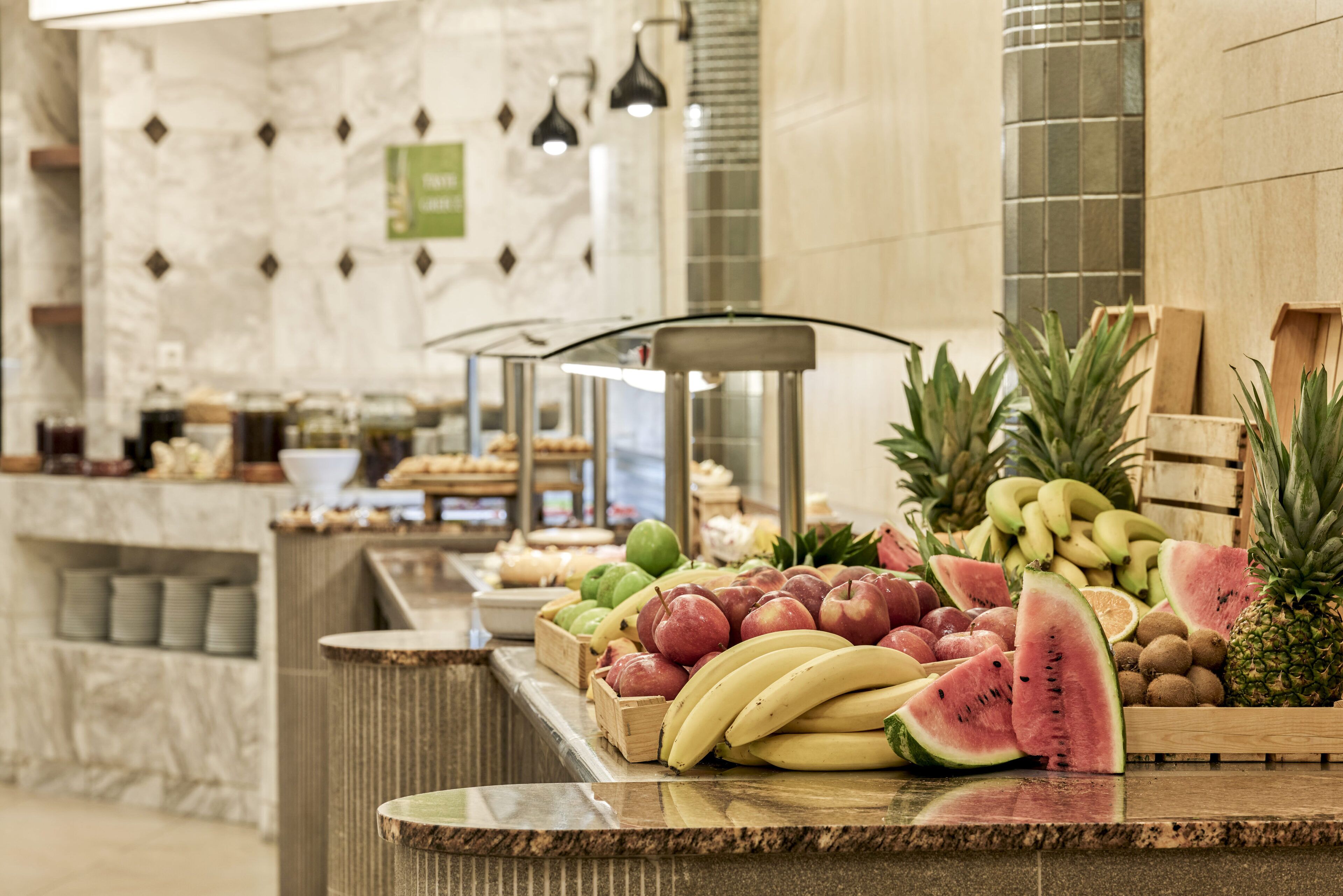 A fruit display at a hotel reception with various fruits like bananas, watermelons, and pineapples.