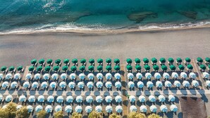 Vista aérea de una playa con hileras de sombrillas y tumbonas.