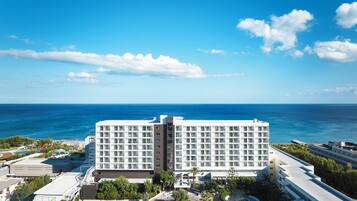 A hotel with a large building, a parking lot, and a view of the ocean.