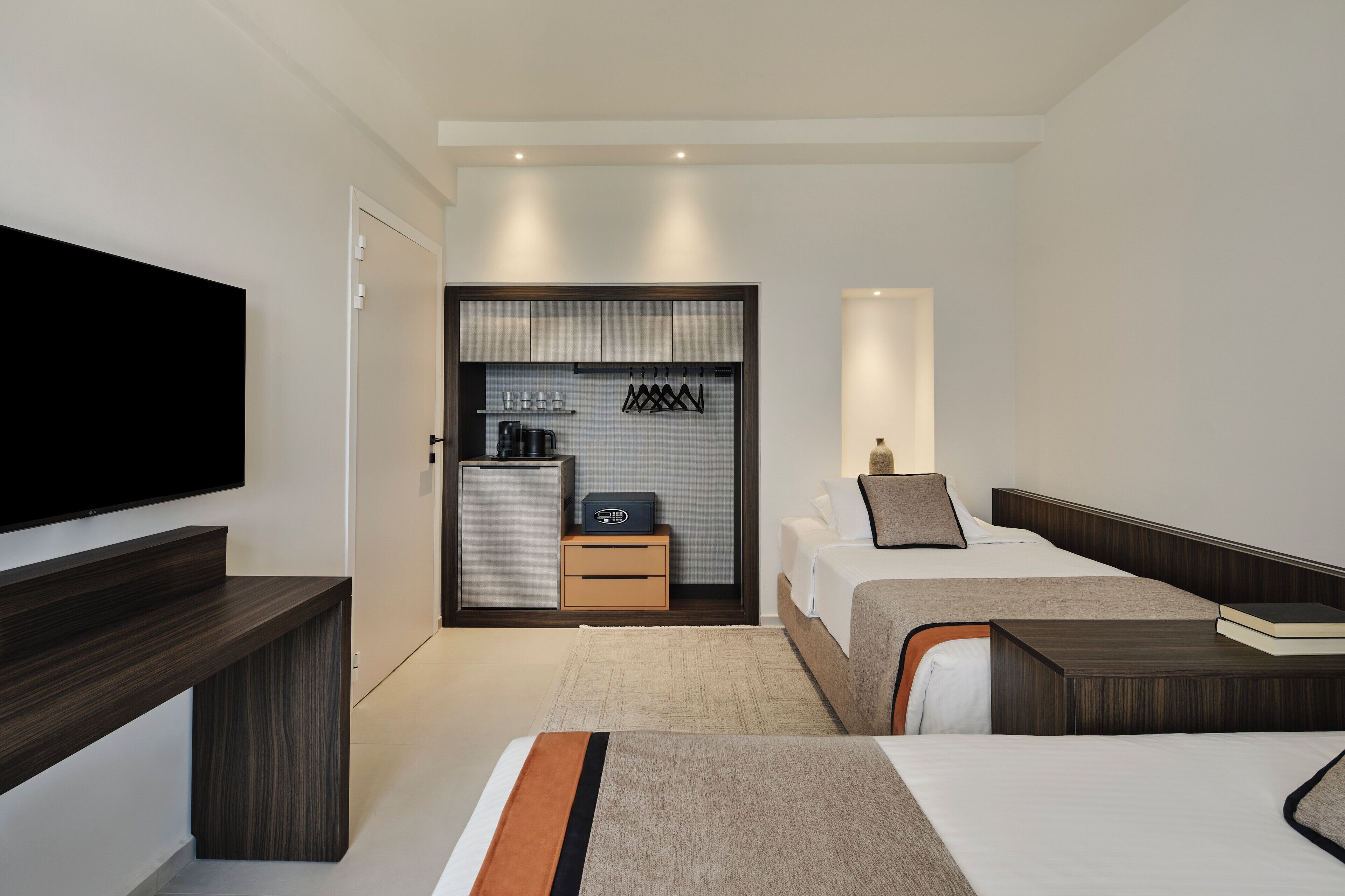 Une chambre d’hôtel moderne équipée d’une télévision à écran plat, d’un lit, d’une table de chevet, d’un bureau, d’une armoire et d’une kitchenette.