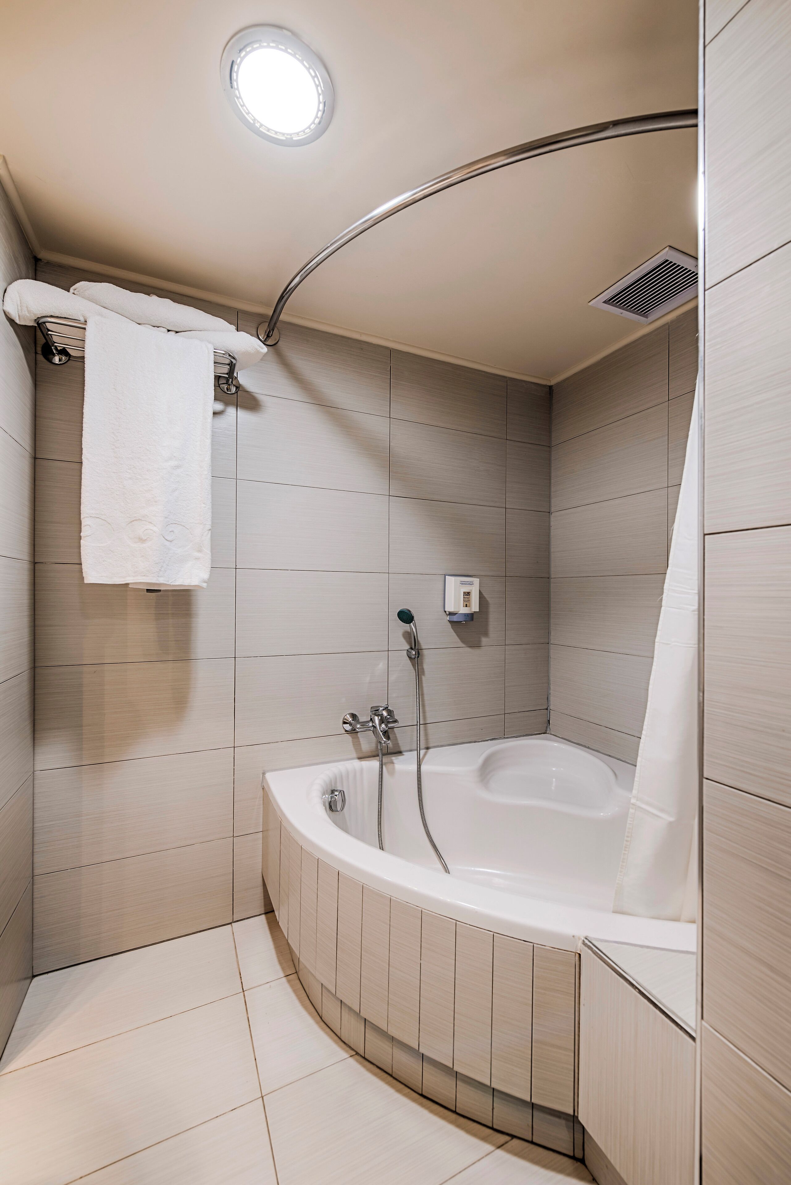 Un baño moderno con una bañera independiente, un perchero y una lámpara en el techo.