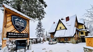 Un bâtiment en bois portant une enseigne indiquant « Cztery Pory Roku » et « SMAKUJ UNAS », ce qui signifie qu’il propose des services d’hébergement et de restauration.