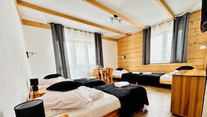 Une chambre d’hôtel avec deux lits, un bureau en bois, une chaise, une petite table et une lampe.