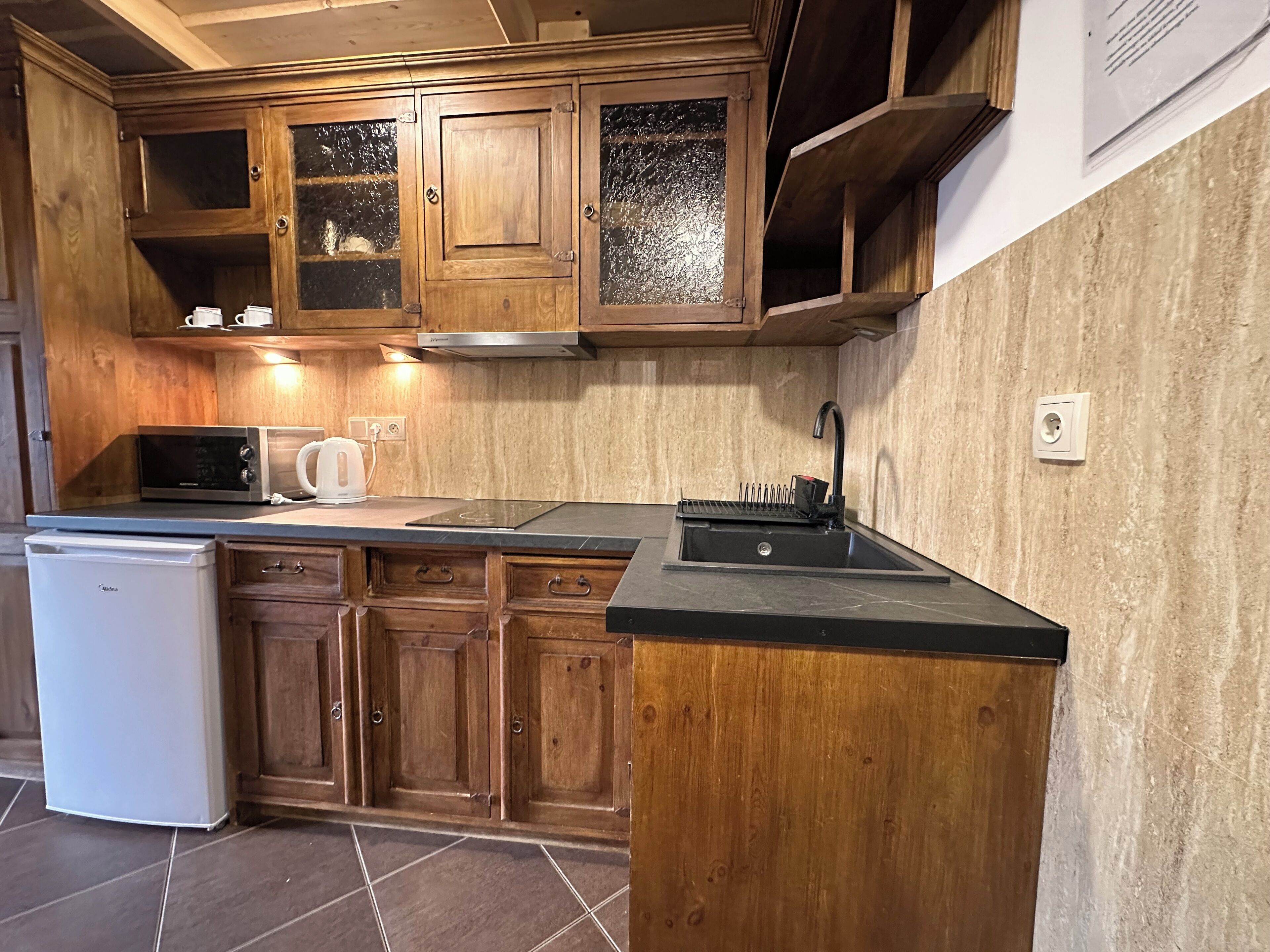 Une cuisine équipée de meubles en bois, d’un four à micro-ondes, d’une bouilloire et d’un évier.