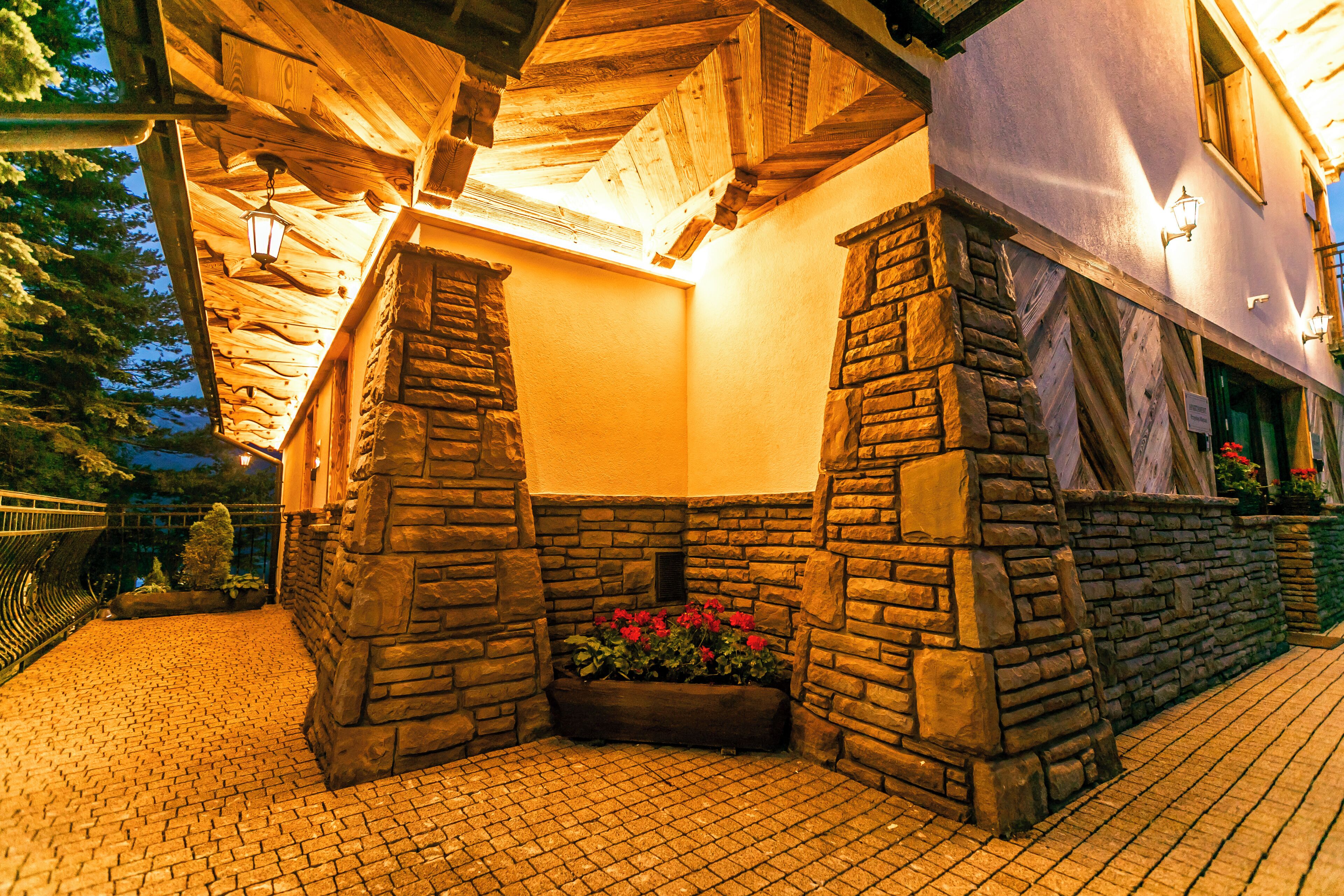 A stone-walled outdoor area with a wooden ceiling and a flower bed.