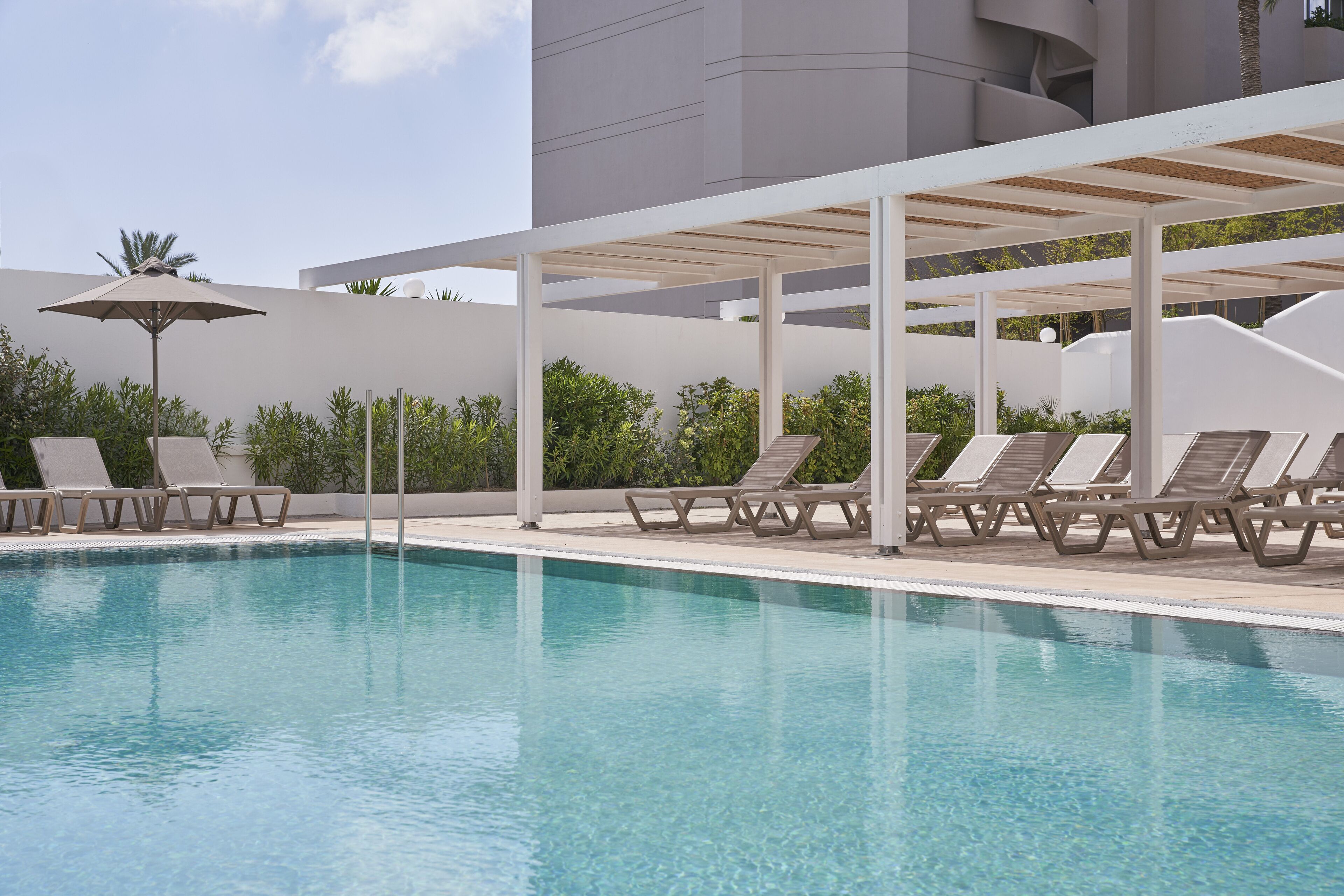 Ein Swimmingpool mit Liegestühlen und einer Pergola.