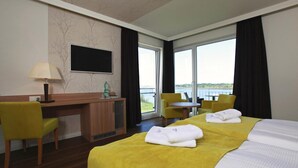 Habitación de hotel con cama, escritorio, silla, mesita y vistas al exterior.