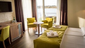 Habitación de hotel con cama, escritorio, silla, mesita y vista al agua.