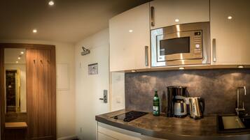 A modern kitchen with a built-in microwave, a coffee maker, and a kettle on the counter.