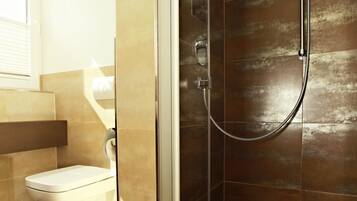 A modern bathroom with a glass-enclosed shower, a toilet, and a sink.