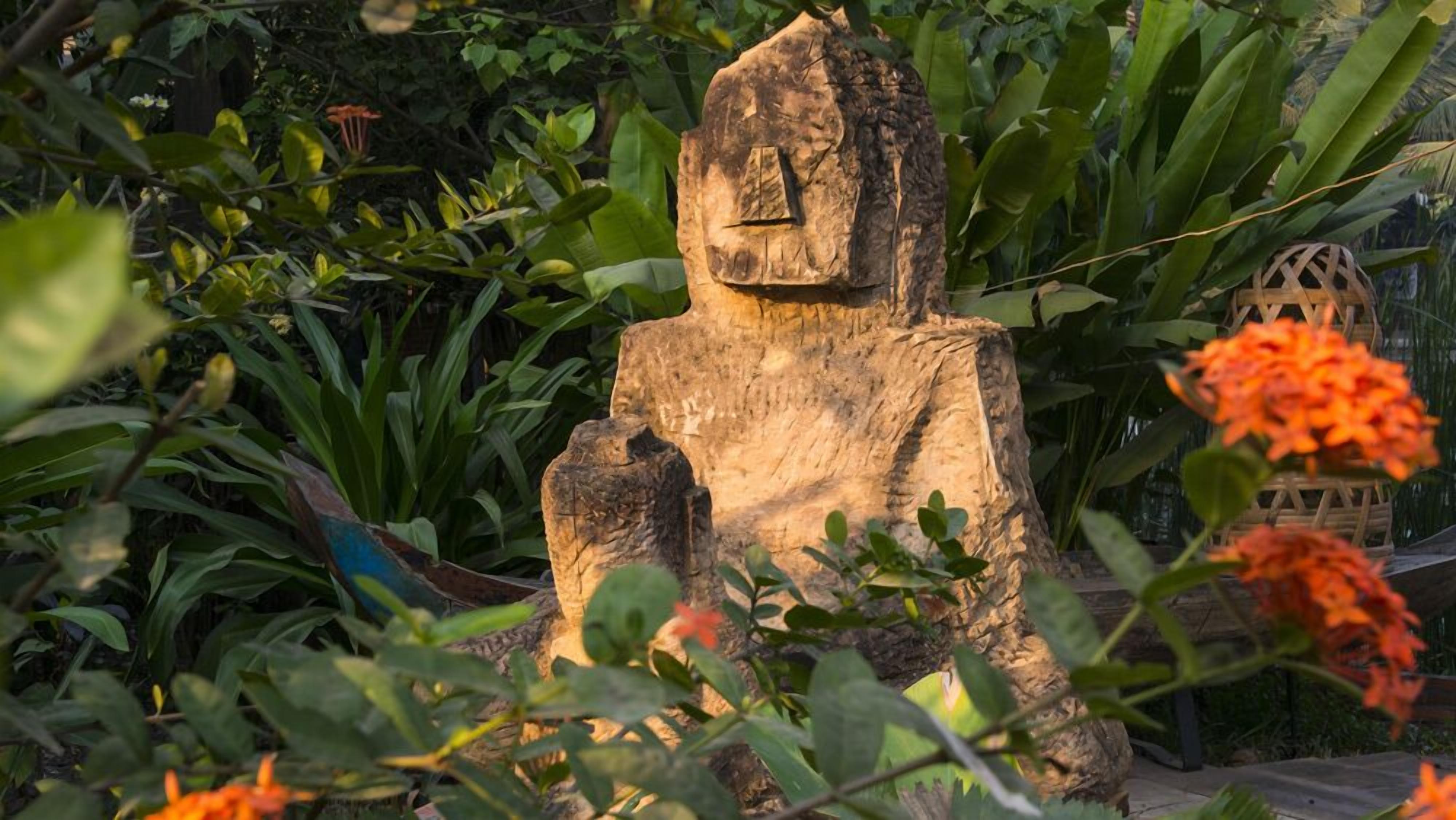 A wooden sculpture in a garden with various plants and flowers.