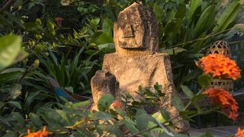 A wooden sculpture in a garden with various plants and flowers.