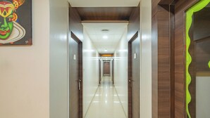 A long, narrow hallway with a polished floor, wooden doors on either side, and a ceiling with recessed lighting.