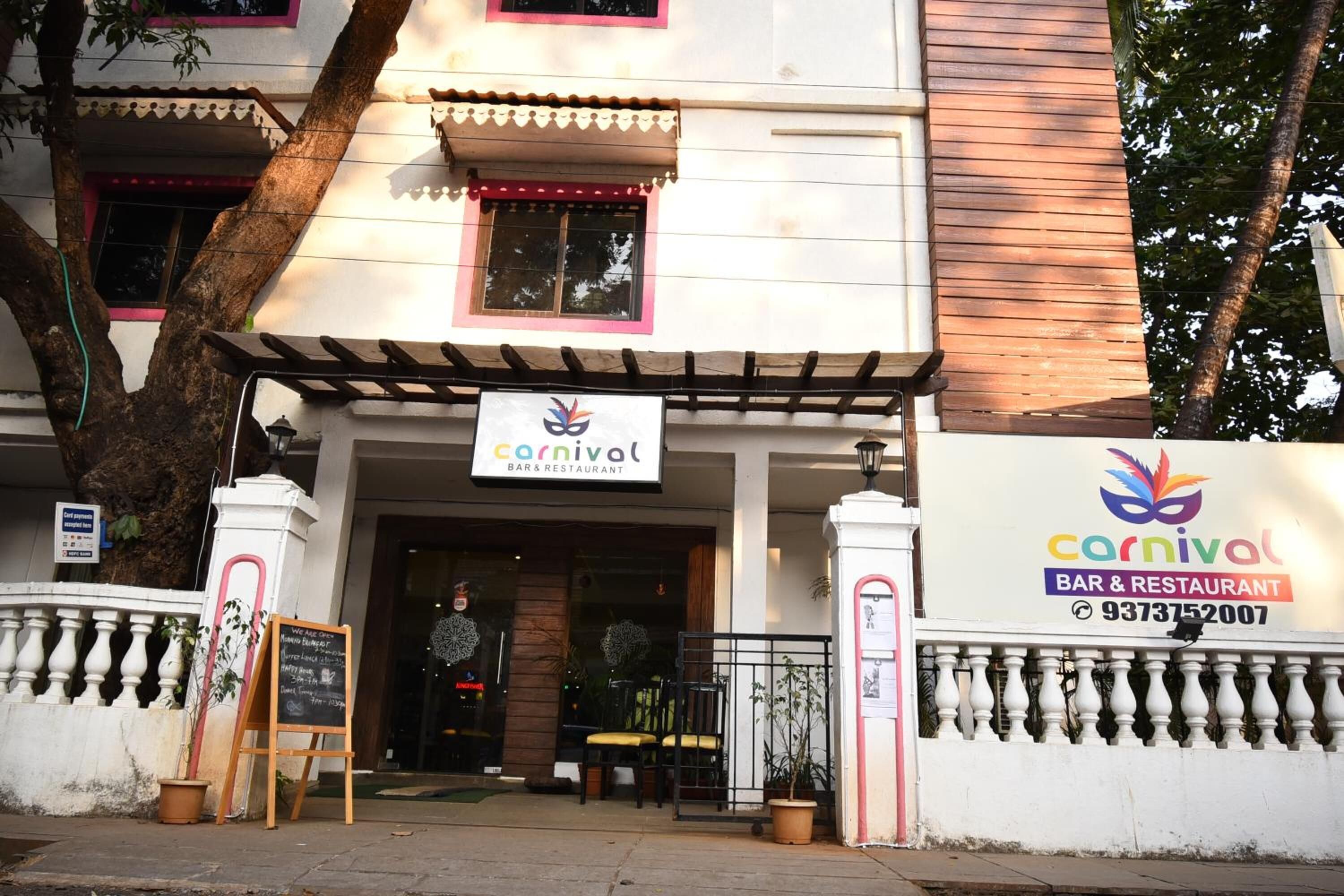 Un edificio con un letrero que indica 'Carnival Bar & Restaurant' y un número de contacto.