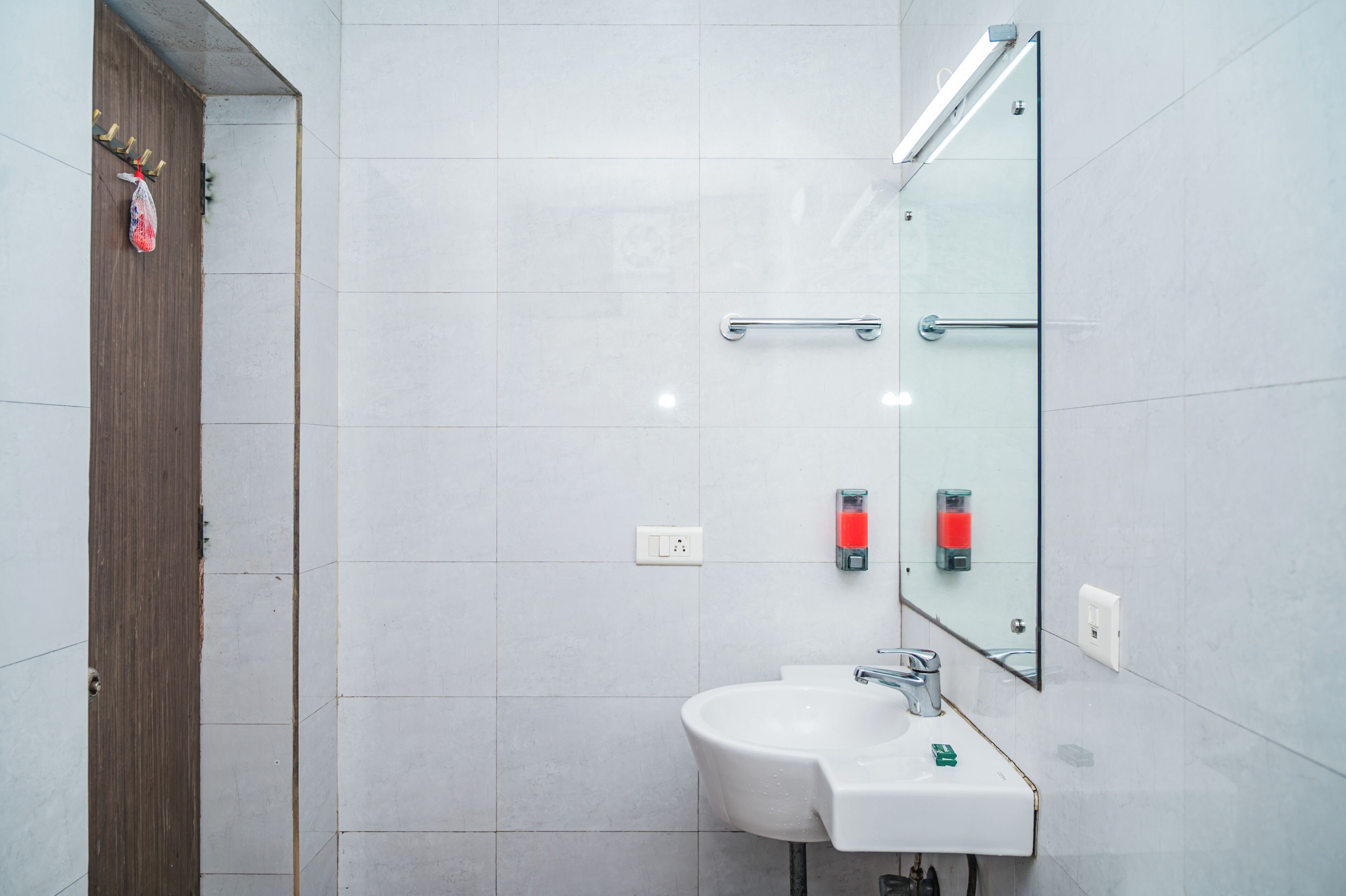 A modern bathroom with a white sink, mirror, and tiled walls.
