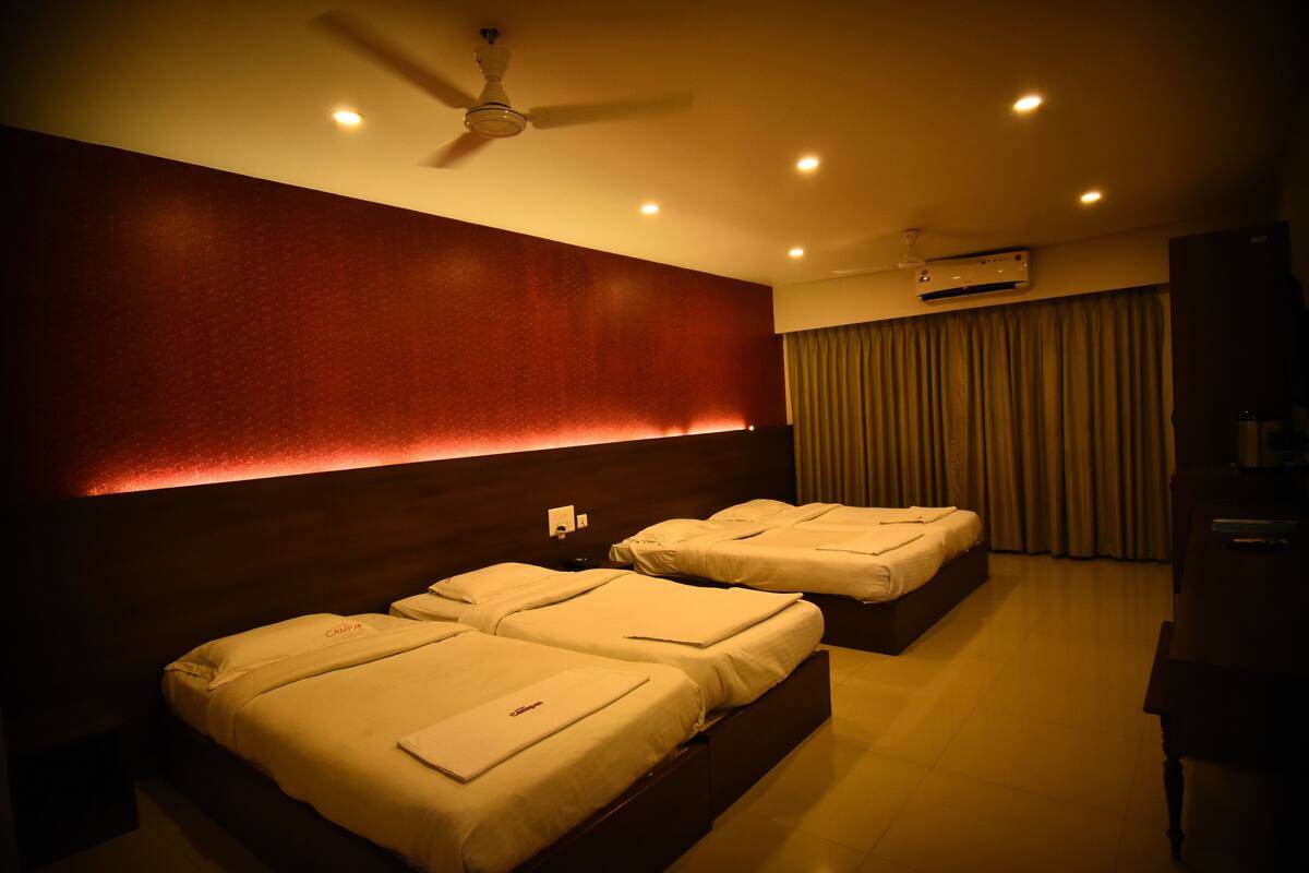 A hotel room with two beds, a ceiling fan, recessed lighting, an air conditioning unit, and a curtain.